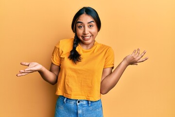 Young latin woman wearing casual clothes clueless and confused expression with arms and hands...