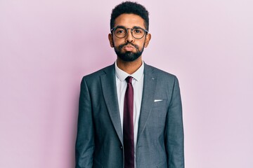 Handsome hispanic business man with beard wearing business suit and tie puffing cheeks with funny face. mouth inflated with air, crazy expression.