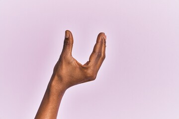 Arm and hand of black middle age woman over pink isolated background picking and taking invisible thing, holding object with fingers showing space