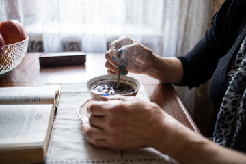Fototapeta na wymiar cup of coffee on the table, old woman's hands stir coffee