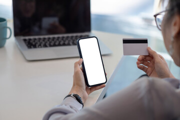 Image of a woman holding a smartphone and credit card in the office. Online shopping concept. Blank white screen. Mockup.
