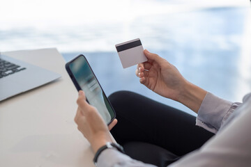 Image of a woman holding a smartphone and credit card in the office