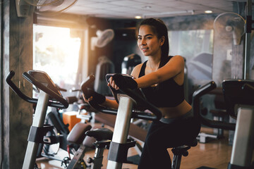 Young Asian woman in exercise clothes spinning bike at gym.
