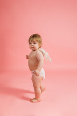 young angel in a diaper and with wings on a pink background with a place for text