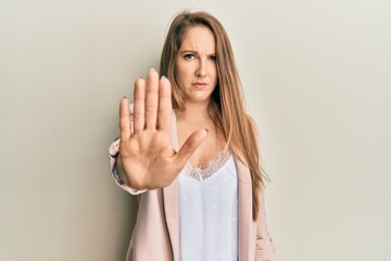 Young blonde woman wearing business jacket and glasses doing stop sing with palm of the hand. warning expression with negative and serious gesture on the face.