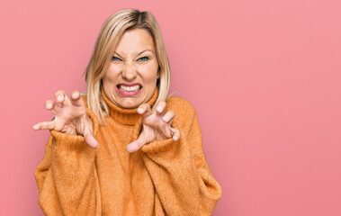 Middle age caucasian woman wearing casual winter sweater smiling funny doing claw gesture as cat, aggressive and sexy expression