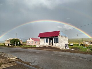 Vibrant double rainbow over a house on the road