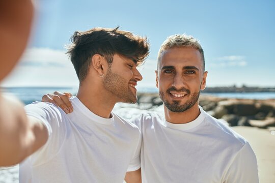 Young gay couple smiling happy making selfie by the smartphone at the beach.