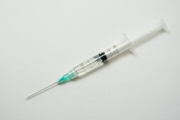 One syringe with liquid on a white surface  