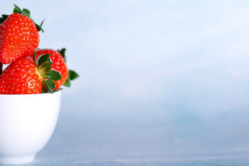 Tasty strawberries on white plate against blue background.