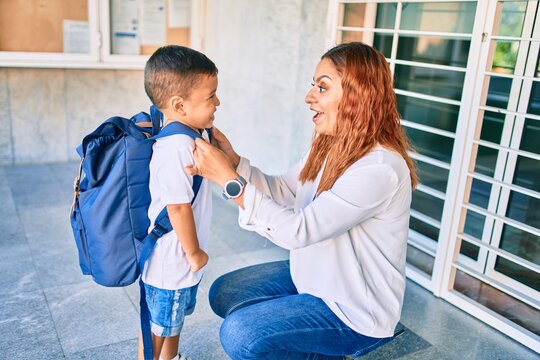 Adorable latin student boy and mom at school. Mother preparing kid putting up backpack.