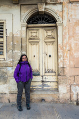 Fototapeta na wymiar Woman with purple jacket and long hair next to a white door