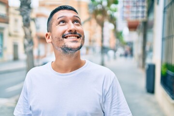 Young hispanic man smiling happy walking at street of city.