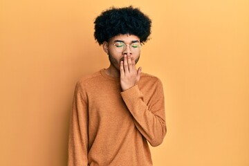 Obraz na płótnie Canvas Young african american man with afro hair wearing casual winter sweater bored yawning tired covering mouth with hand. restless and sleepiness.