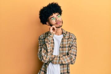 Fototapeta na wymiar Young african american man with afro hair wearing casual clothes thinking concentrated about doubt with finger on chin and looking up wondering