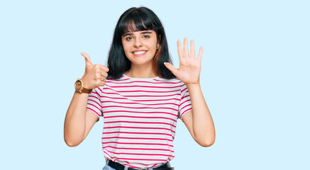 Obraz na płótnie Canvas Young hispanic girl wearing casual clothes showing and pointing up with fingers number six while smiling confident and happy.