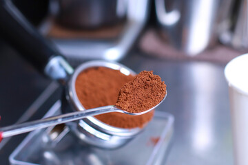 Close-up, coffee holder on the kitchen scale, ground coffee beans in the filter, Coffee in the spoon, background blurred