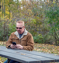 A middle-aged gay couple goes for a walk in the park with their dog in the autumn.