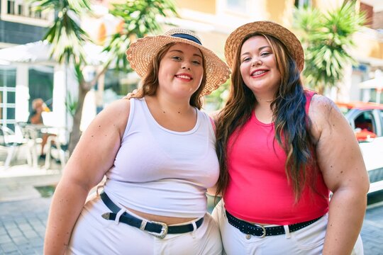 Two plus size overweight sisters twins women hugging together outdoors