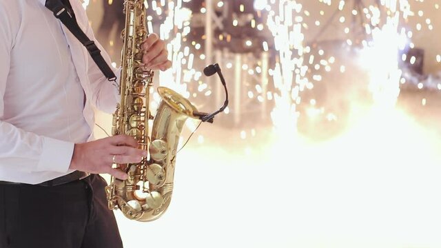 Saxophone player performing a solo on wedding party. Saxophonist play on golden saxophone. Live performance. Musician playing alto saxophone on a gig. Wedding day. First wedding dance.