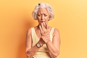 Senior grey-haired woman wearing casual clothes suffering pain on hands and fingers, arthritis...