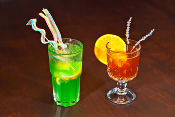 Orange and green cocktail on a wooden table. Sharpness on fruit cocktails with lime and orange. Alcoholic drink close up.