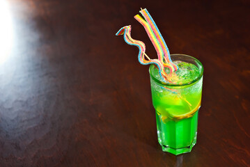 Green cocktail on a wooden table. Sharpness on a fruit cocktail with lemon. Alcoholic drink close up.