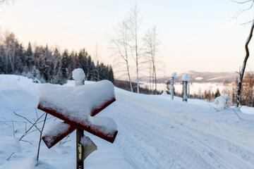 Sign marking a snowmobile trail in foreground and landscape in background.