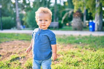 Cute and happy little boy having fun at the park on a sunny day. Beautiful blonde hair male toddler playing outdoors