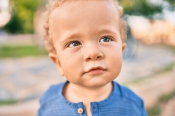 Cute and happy little boy having fun at the park on a sunny day. Beautiful blonde hair male toddler playing outdoors