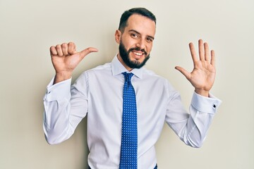 Young man with beard wearing business tie showing and pointing up with fingers number six while smiling confident and happy.