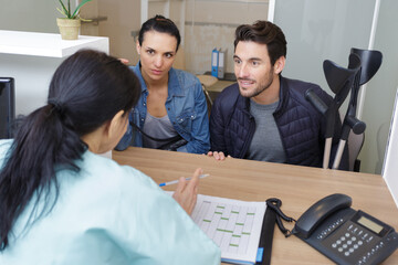 positive couple talking with secretary at reception in the clinic