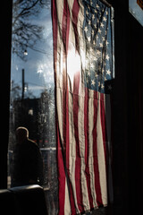 Fototapeta na wymiar Distressed Vintage Tattered American Flag With Sun Flare Inside Restaurant
