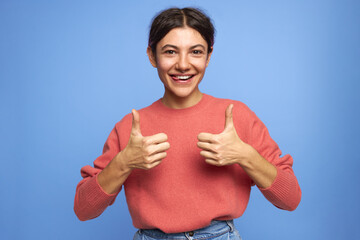Isolated shot of optimistic positive young Caucasian female with nose ring making thumbs up gesture...
