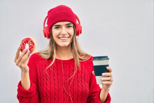 Young hispanic woman having breakfast using headphones at the city.