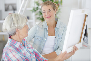 Obraz premium senior woman looks at photo in frame with daughter