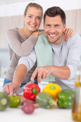 Obraz na płótnie Canvas happy couple cooking vegetables in kitchen