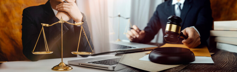 Justice and law concept.Male judge in a courtroom with the gavel, working with, computer and docking keyboard, eyeglasses, on table in morning light