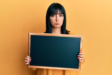 Young hispanic woman holding blackboard depressed and worry for distress, crying angry and afraid. sad expression.