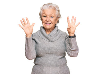 Senior grey-haired woman wearing casual winter sweater showing and pointing up with fingers number nine while smiling confident and happy.