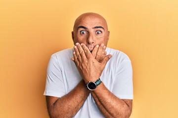 Mature middle east man wearing casual white tshirt shocked covering mouth with hands for mistake. secret concept.