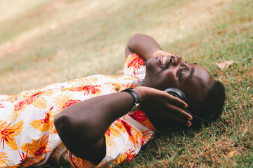 African man lying and listening  music from smartphone with earphones