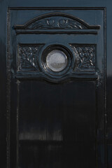 Upper part of an old-fashioned stately and beautifully decorated dark green front door with a round...