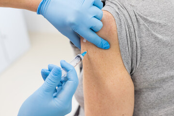 doctor in protective gloves holding syringe and making injection to senior patient.Elderly vaccination concept. Medical worker vaccinating an elderly patient against flu, influenza, pneumonia or