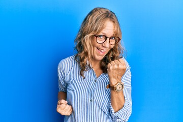 Middle age blonde woman wearing casual clothes and glasses celebrating surprised and amazed for...
