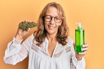Middle age blonde woman holding medical cannabis cosmetic winking looking at the camera with sexy...