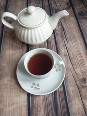 on the table a white porcelain teapot and a white cup of tea