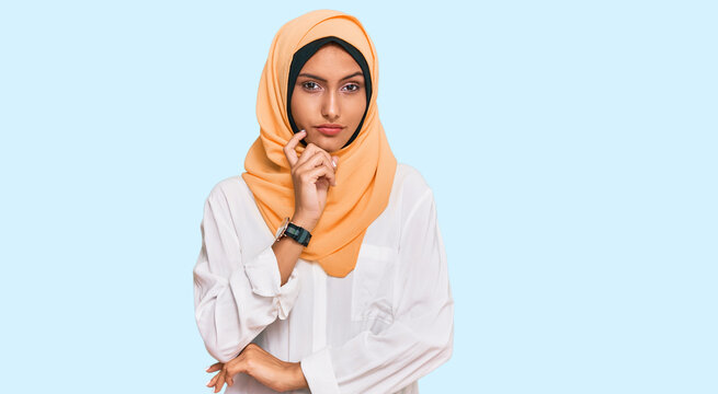 Young Brunette Woman Wearing Traditional Islamic Hijab Scarf Serious Face Thinking About Question With Hand On Chin, Thoughtful About Confusing Idea