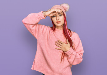 Young caucasian woman wearing casual clothes and wool cap touching forehead for illness and fever, flu and cold, virus sick