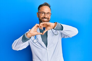 Handsome middle age man wearing doctor uniform and stethoscope smiling in love doing heart symbol...
